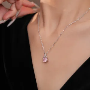 Close-up of elegant silver necklace with round pink zircon pendant worn on neck