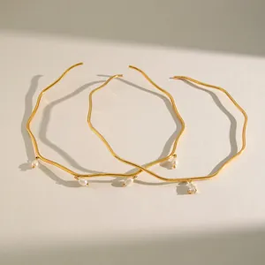 Dettaglio di eleganti collane ondulate in acciaio inossidabile dorato con perle e cristalli