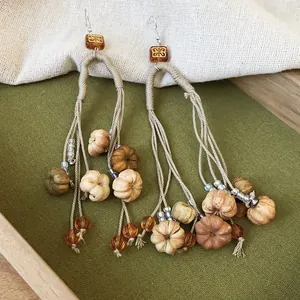 Close-up of vintage autumn pumpkin tassel earrings with hemp rope and amber beads