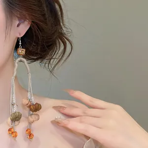 Close-up of vintage autumn long tassel earrings featuring detailed pumpkin charms and warm tones