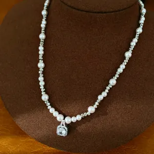 Detail view of a beaded pearl necklace with a square-cut zircon pendant on a brown bust