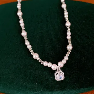 Elegant pearl necklace detail with sparkling square zircon pendant on green velvet