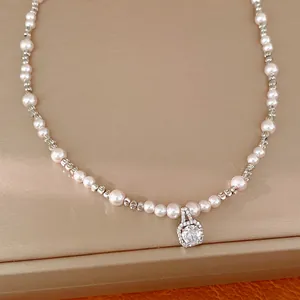 Detail of beaded pearl necklace featuring a square zircon pendant in a soft gold setting
