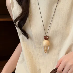 Vue détaillée d'un collier pendentif chat en bois avec des pampilles perlées uniques