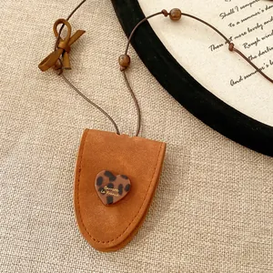 Nahaufnahme eines braunen Wildleder-Halskettenbeutels mit einem Leoparden-Resin-Herz