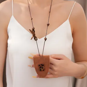 Nahaufnahme einer braunen Halskette mit Lederbär-Anhänger und Harzdetail an einem Model