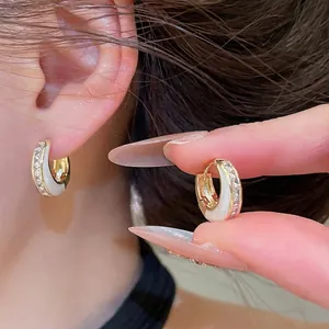 Elegant gold-tone geometric hoop earrings with white enamel and sparkling cubic zirconia