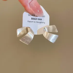 Dettaglio di orecchini a lobo minimalisti in argento 925 spazzolato a forma di C su carta