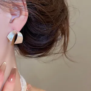 Primo piano di orecchini minimalisti a forma di C in argento spazzolato indossati da modella
