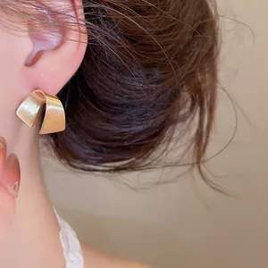 Primo piano dettagliato di un orecchino a forma di C in oro spazzolato su una modella
