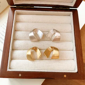 Dettaglio di orecchini a cerchio a C minimalisti spazzolati opachi in oro e argento