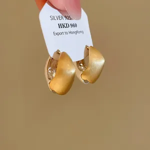 Nahaufnahme von gebürsteten zweifarbigen geometrischen Creolen auf Karte, gold und silber