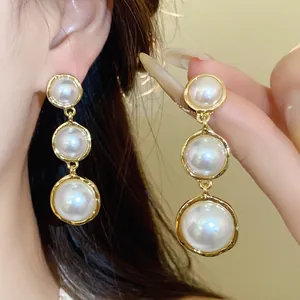 Detail view of French style triple graduated pearl drop earrings with golden luster.