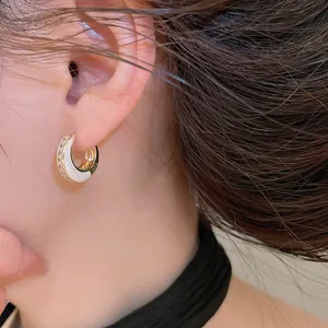 Detailansicht eines zweifarbigen geometrischen Creolen-Ohrrings mit weißem Inlay