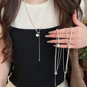 Detail van zilveren asymmetrische ster- en hart-hangers met elegante parelkralen
