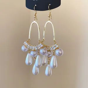 Macro view of elegant French style drop earrings with white pearls and gold tassels.