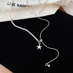 Detail van zilveren asymmetrische ketting met parels en een sterhanger.