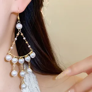 Detailed close-up of French luxury pearl beaded tassel earrings worn by a model