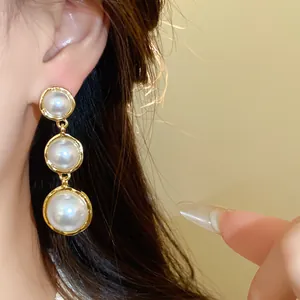Elegant French style detail shot of graduated round pearl earrings with gold frames.