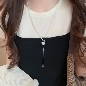 Detailweergave van een zilveren hartjesketting met een asymmetrische parelketting