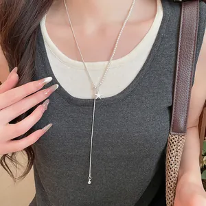 Gedetailleerde opname van een zilveren asymmetrische sterhanger ketting met witte parels