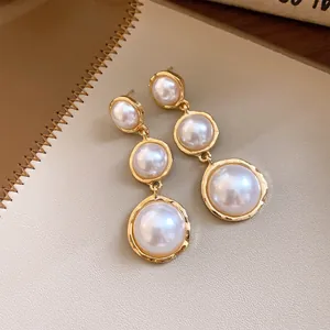 Close-up of French luxury triple pearl drop earrings with elegant gold-tone framing