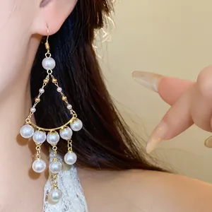 Detailed macro view of elegant French luxury pearl beaded tassel earrings worn on model's ear