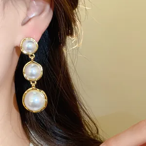 Close-up of elegant French style triple pearl drop earrings on a model