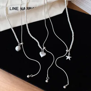 Detail van zilveren asymmetrische kettingen met ster hart hangers en witte parels
