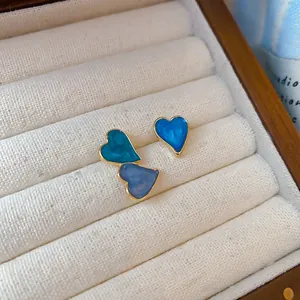Detailed view of asymmetric heart-shaped stud earrings with blue drip oil enamel