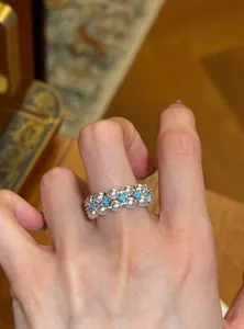 Nahaufnahme eines luxuriösen Perlenrings mit türkisfarbenen Akzenten an einem Finger
