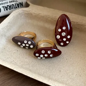 Macro detail of vintage oval enamel rings with sparkling rhinestone inlay on a tan tray