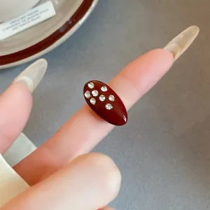 Detailed close-up of a vintage dark red oval enamel ring with sparkling rhinestone inlays