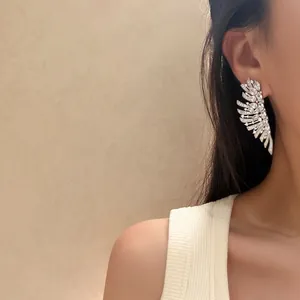 Gros plan de boucles d'oreilles élégantes en zircone cubique en forme d'ailes.