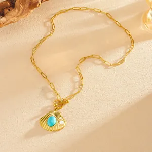 Gedetailleerde weergave van gouden schelphanger met turquoise en parels aan ketting