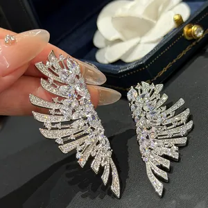 Gros plan de boucles d'oreilles de luxe en zircon étincelant en forme d'ailes pour banquet
