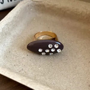 Macro detail view of a vintage oval enamel ring featuring sparkling rhinestone accents
