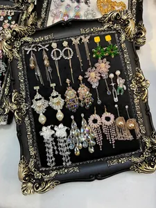 Detailed view of various vintage zircon flower and tassel earrings on a black frame