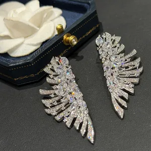 Vue détaillée de luxueuses boucles d'oreilles en forme d'ailes avec zircons brillants.