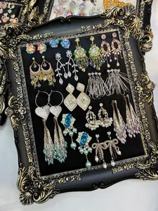 Collection of vintage zircon and pearl drop earrings displayed in an ornate frame