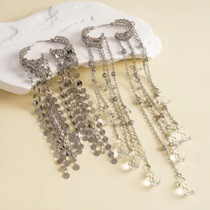 Detailed view of metallic sequin and glass water drop tassel earrings on a white stone prop.