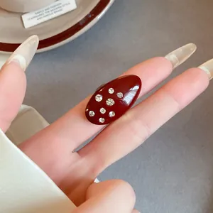 Close-up detail of a vintage red enamel oval ring with sparkling rhinestones on a finger