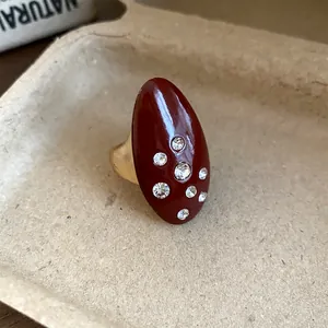 Macro detail of a vintage oval ring featuring burgundy enamel and inlaid rhinestones