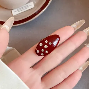Close-up detail of a vintage burgundy enamel ring with sparkling rhinestone accents.