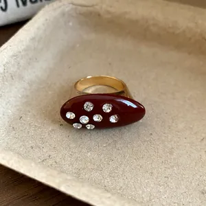 Close-up detail of a vintage oval ring featuring dark red enamel and sparkling rhinestones