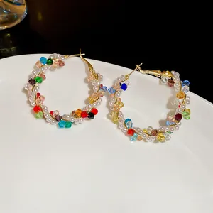 Detailed view of elegant gold hoop earrings with multi-color crystals and white pearls.