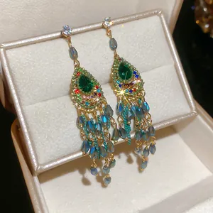 Detailed macro view of vintage earrings featuring green teardrop stones and blue tassels