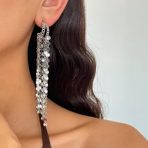 High-quality close-up of silver tassel earrings with shiny sequins worn on model's ear