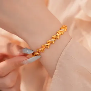 Nahaufnahme eines 24k vergoldeten Herzarmbands mit Zirkonia und gebürsteter Textur