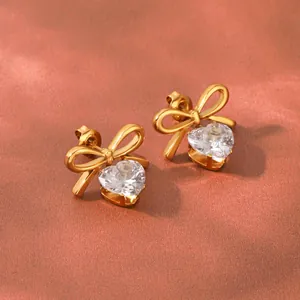 Close-up detail of 18k gold plated stainless steel bow stud earrings with heart zircon